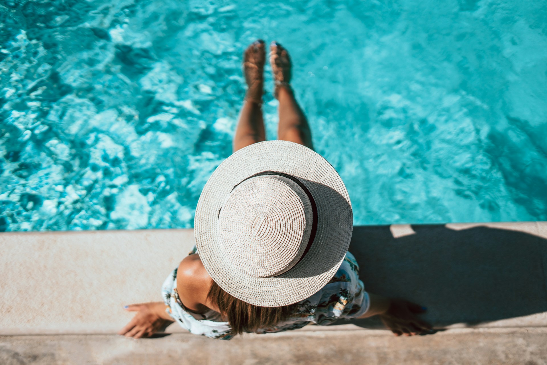 a woman in a hat is sitting by a pool