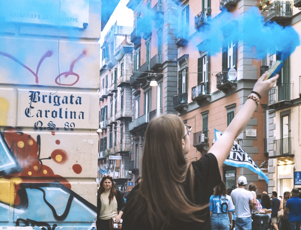 a woman holding a blue smoke bomb in the air