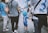 A group of people walking down a street, many wearing matching sports shirts. A young child adorned in a blue sports outfit with a blue wig stands out amongst the crowd. The atmosphere appears lively, possibly part of a sports event or parade.