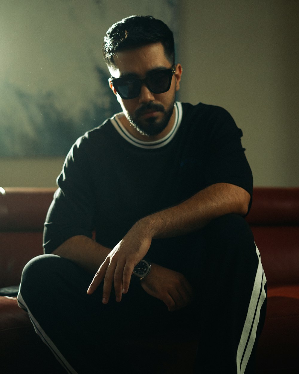 a man sitting on a red couch wearing sunglasses