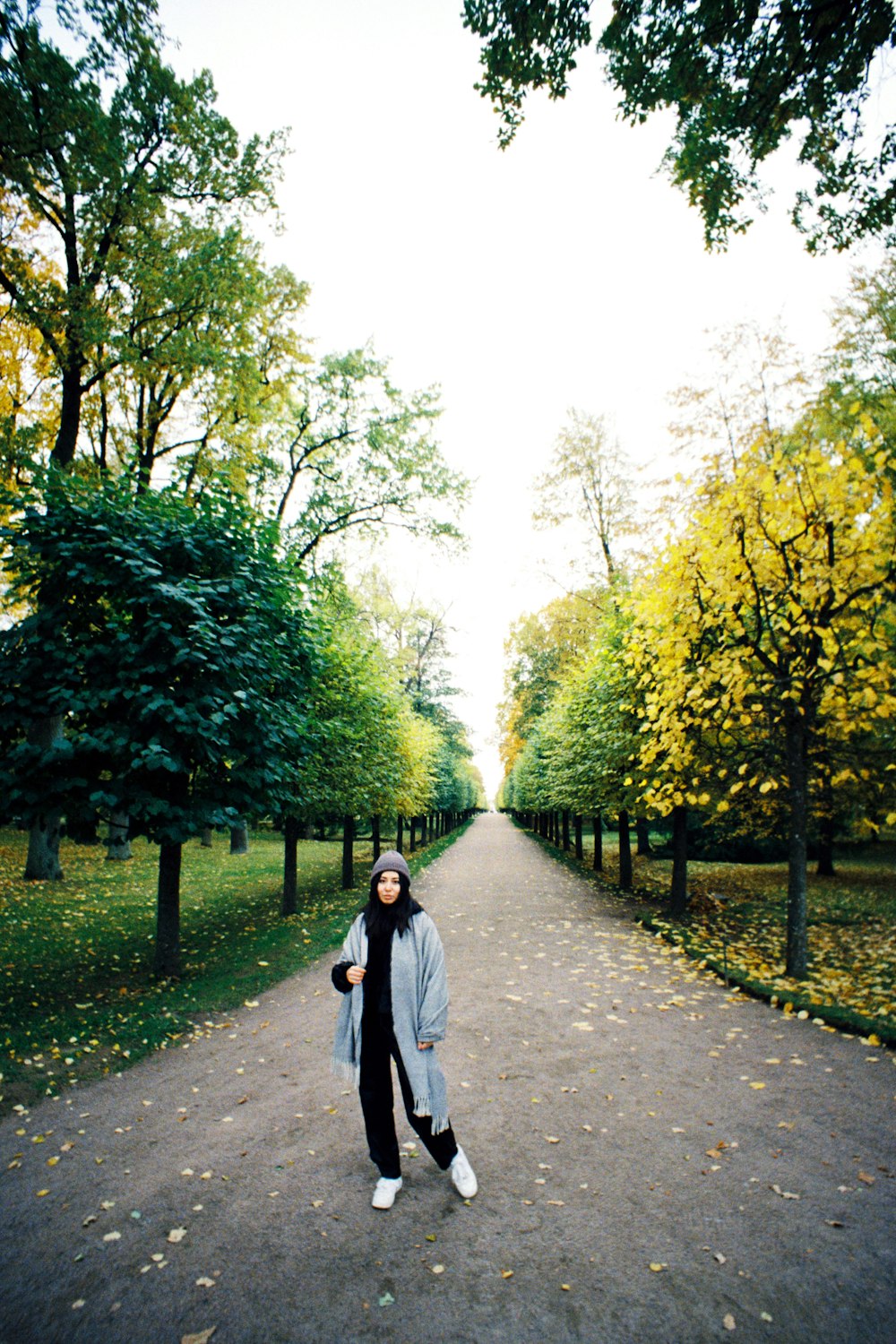 a woman standing on a road surrounded by trees