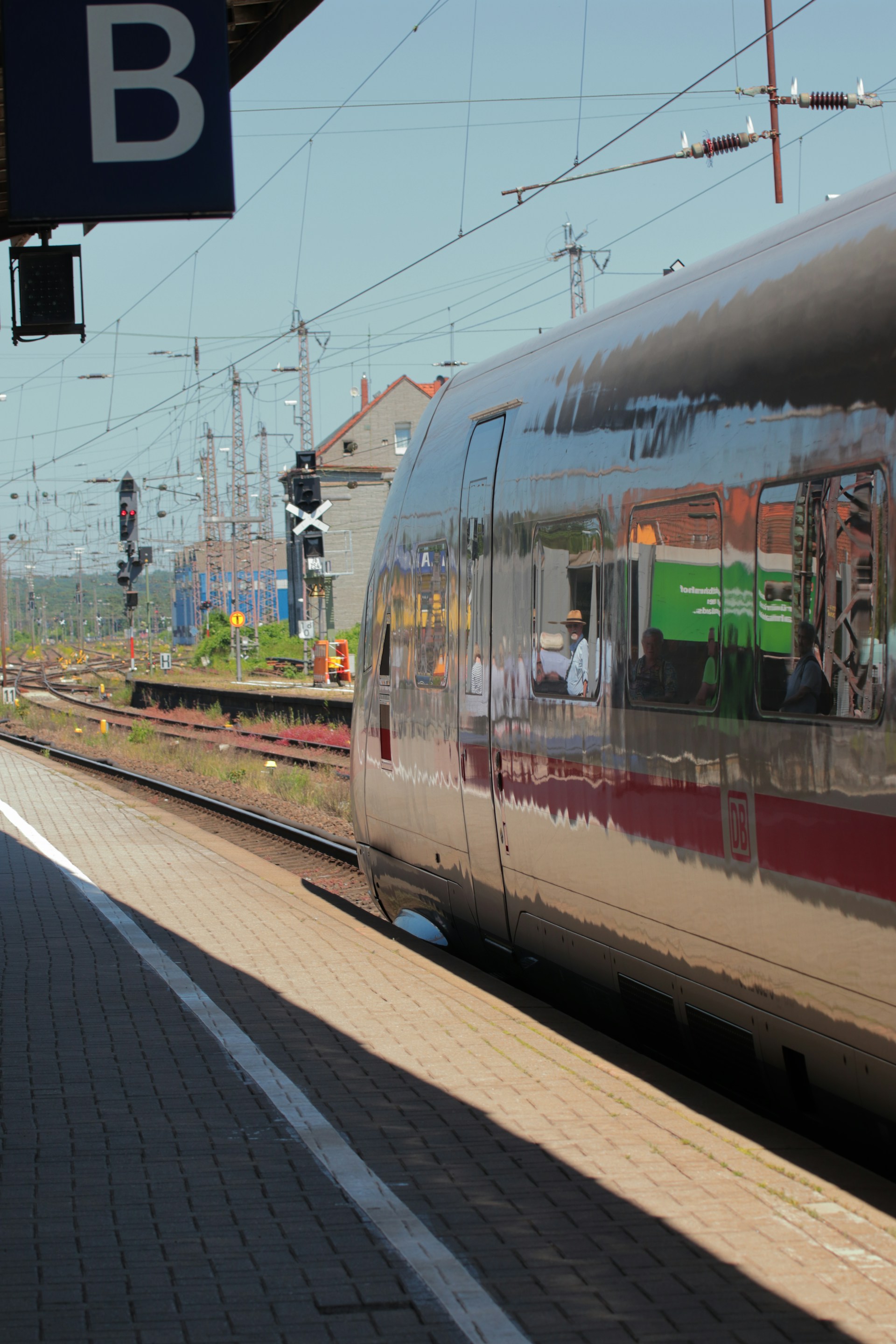 a silver train traveling down train tracks next to a train station