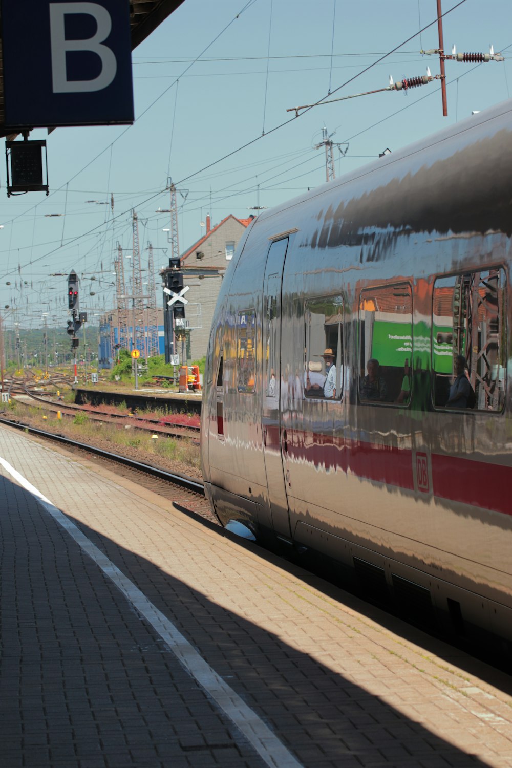 Un tren plateado que viaja por las vías del tren junto a una estación de tren