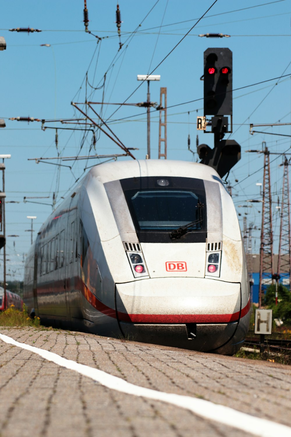 a white train traveling down train tracks next to a traffic light