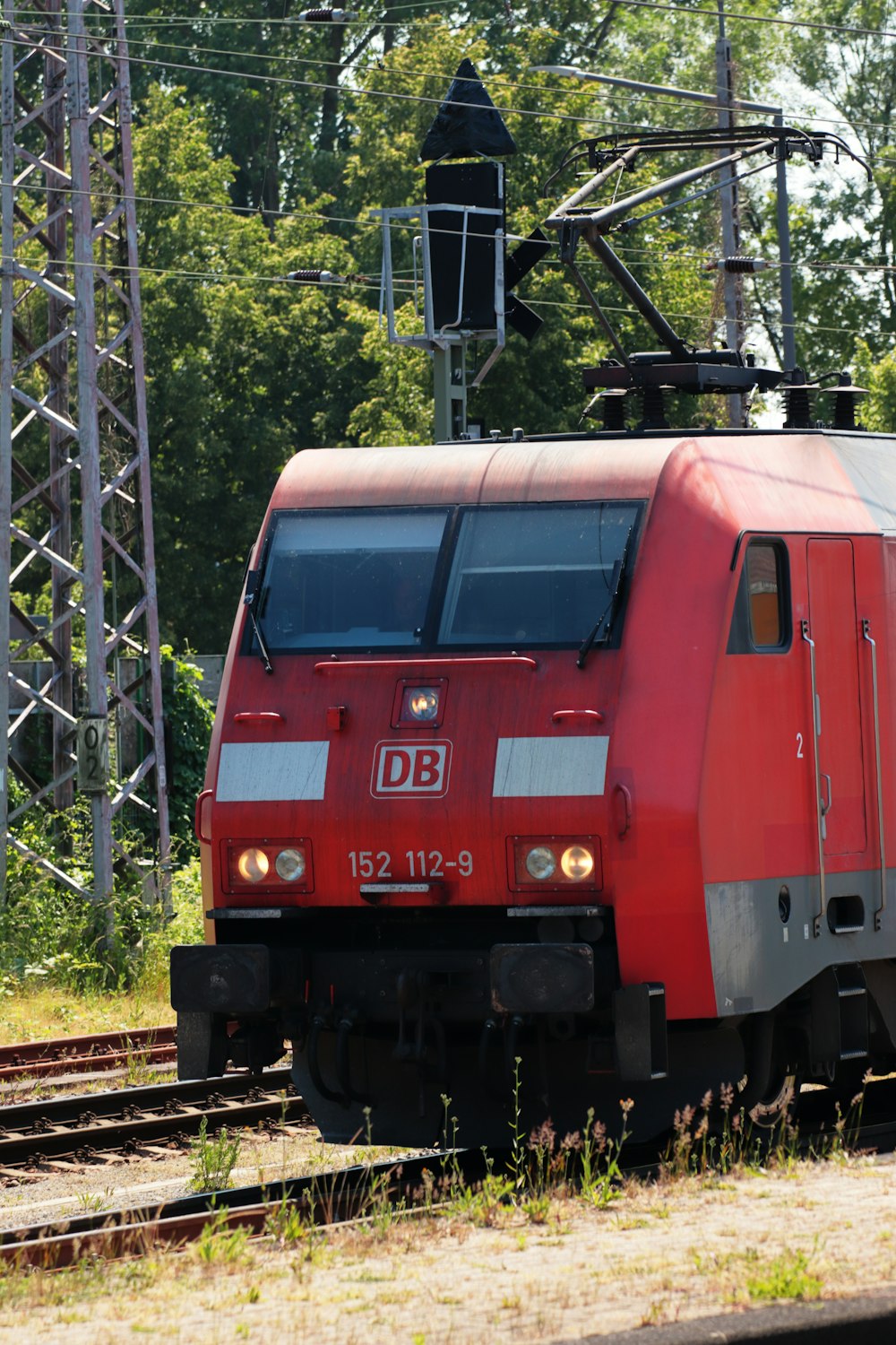 Un tren rojo que viaja por las vías del tren junto a un bosque