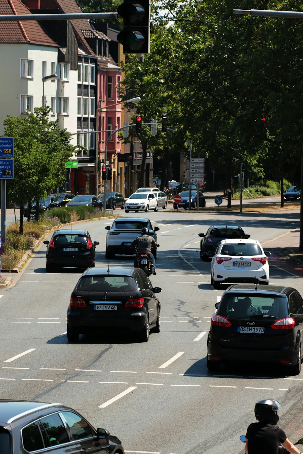 eine gruppe von autos, die eine straße neben hohen gebäuden entlang fahren