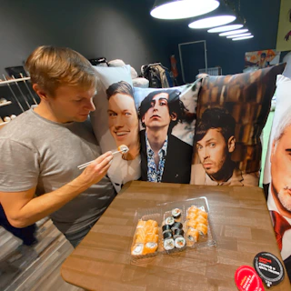 A vibrant photo of Chase enjoying a sushi meal with chopsticks in hand, smiling brightly.