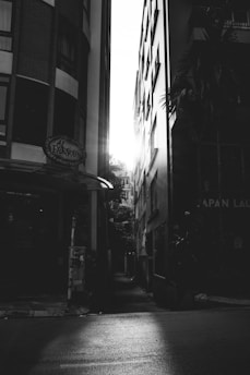 Sunlight filtering through narrow alleys in Bangkok, highlighting worn textures and fleeting reflections.
