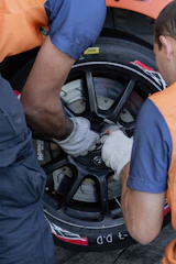 two men working on a tire on a car