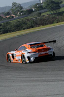 an orange and white car driving on a race track