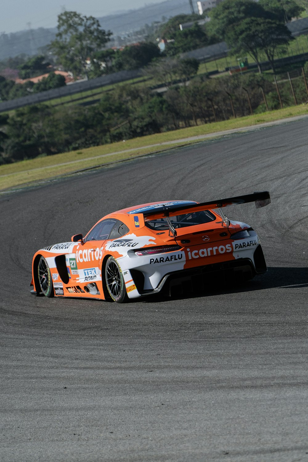 Un coche naranja y blanco conduciendo en una pista de carreras