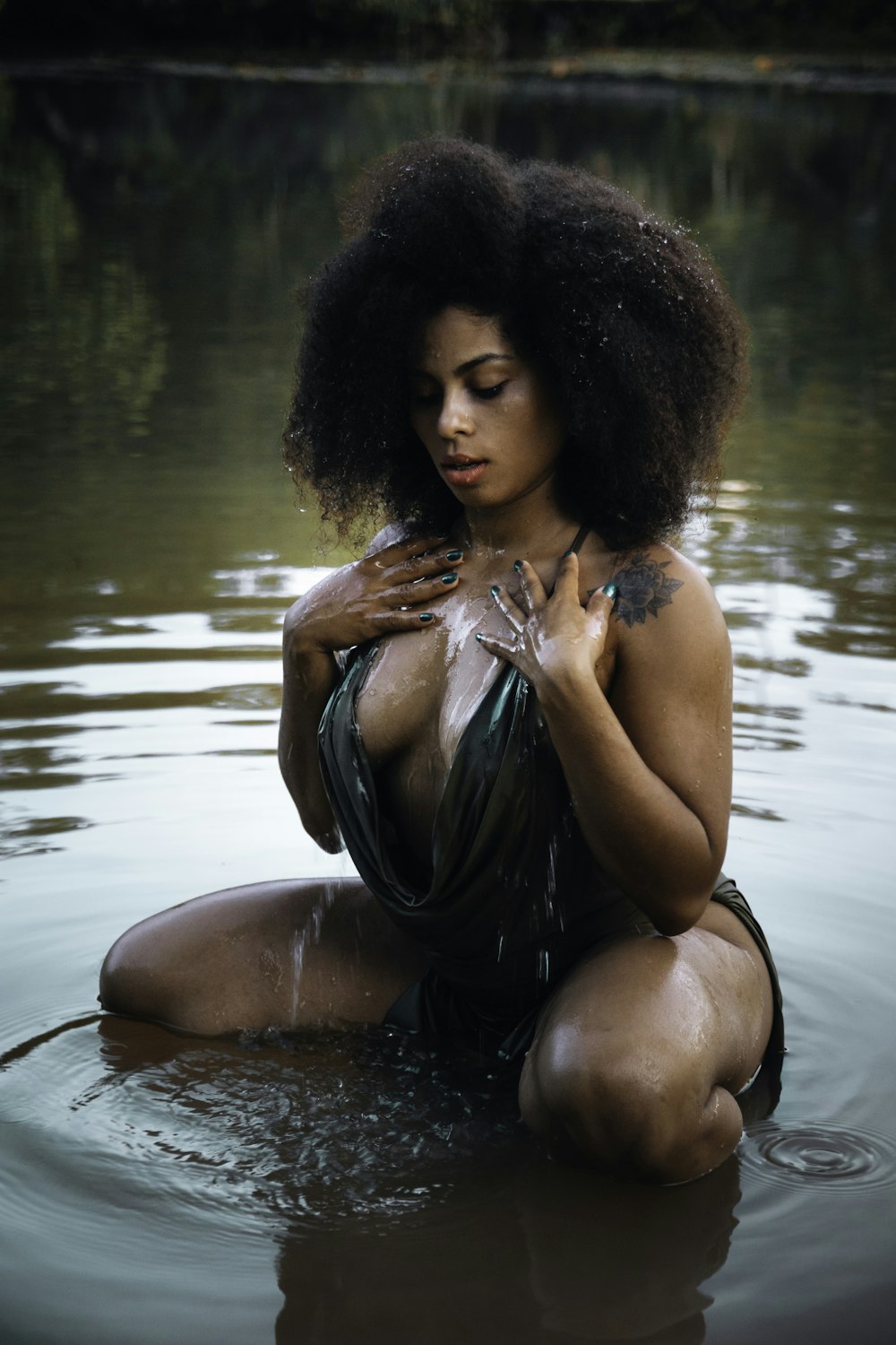 a woman sitting in the water with her hands on her chest