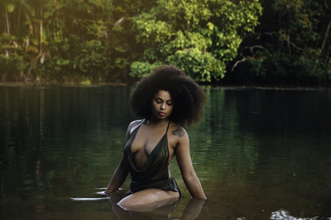 a woman in a body of water with trees in the background
