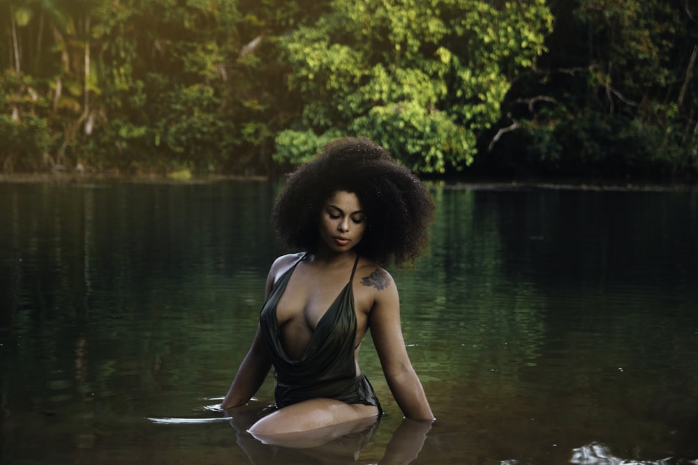 a woman in a body of water with trees in the background