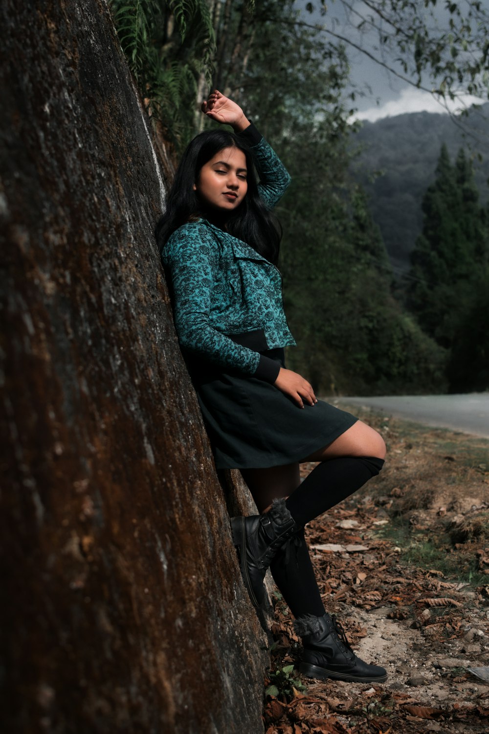 a woman leaning against a tree in a forest