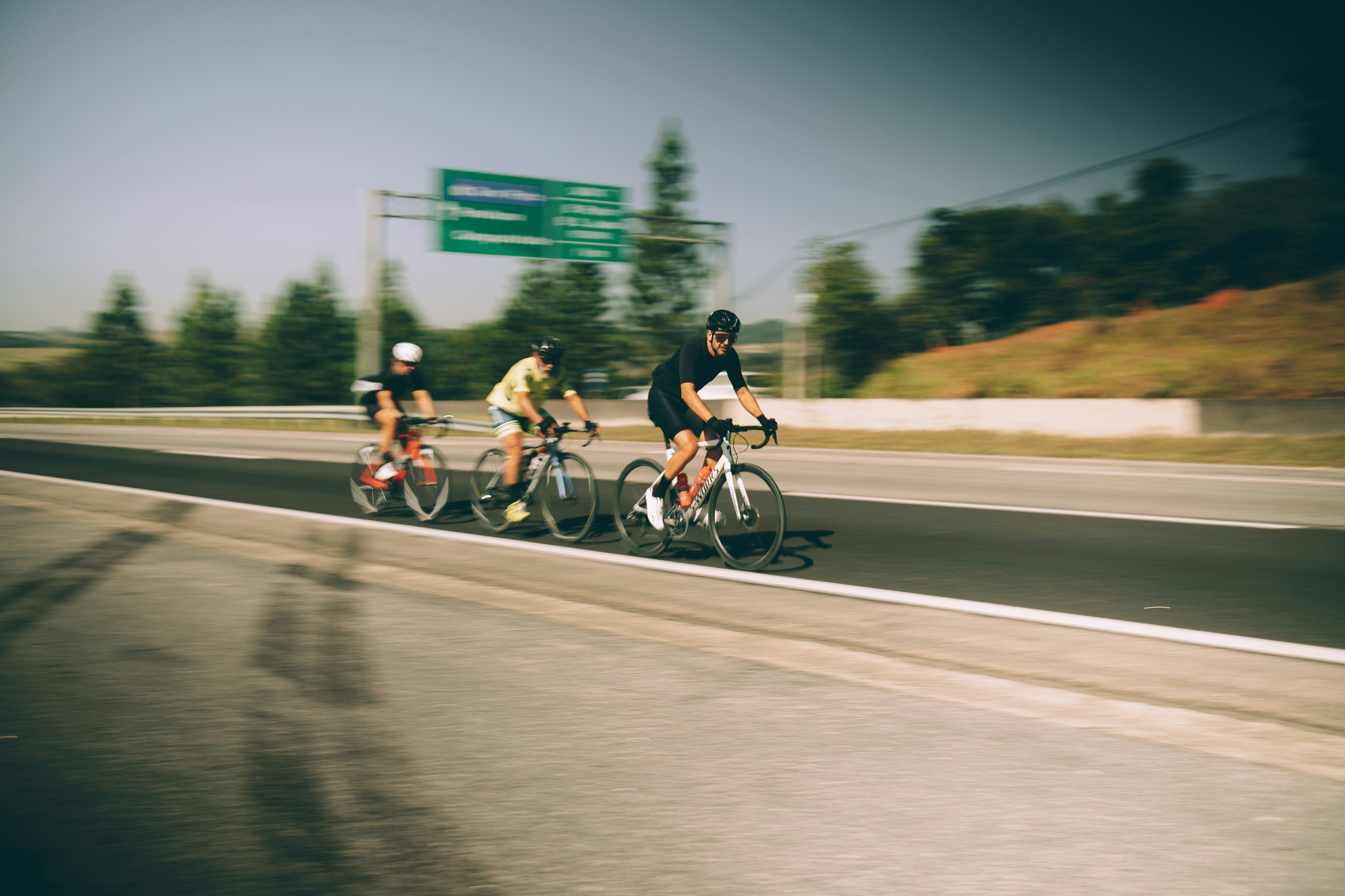three bicyclists are riding down the highway