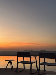 A stylish patio rocking chair with cushioned seating set against a sunny garden backdrop.