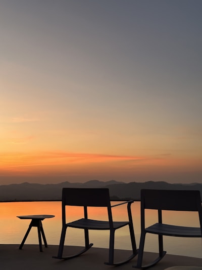A stylish patio rocking chair with cushioned seating set against a sunny garden backdrop.