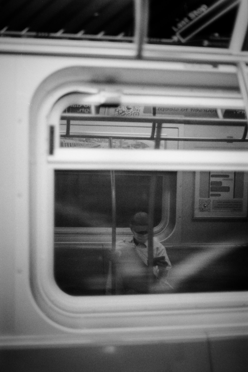 a black and white photo of a person sitting on a train