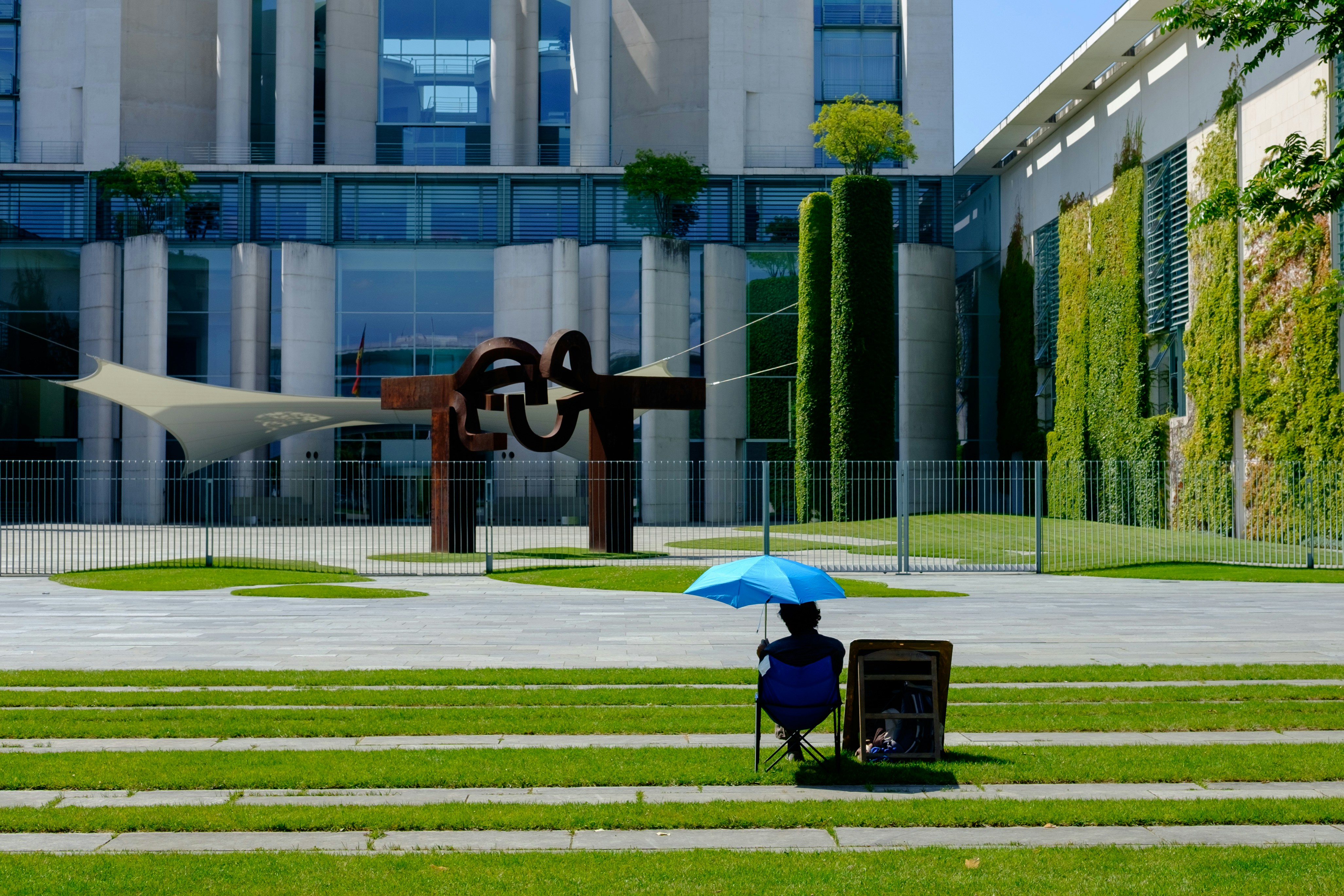 a person sitting in a chair with a blue umbrella