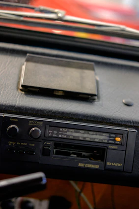 A friendly technician installing an SRS FM car radio inside a car, with a smiling senior citizen watching.