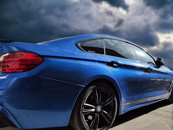 a blue car parked in a parking lot under a cloudy sky
