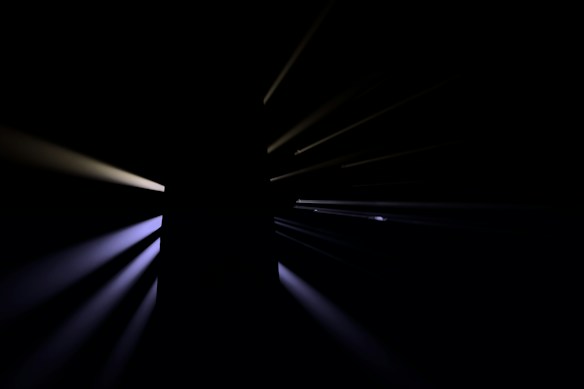 A dark background with streaks of light radiating outward from a central point, creating a dramatic and mysterious effect.