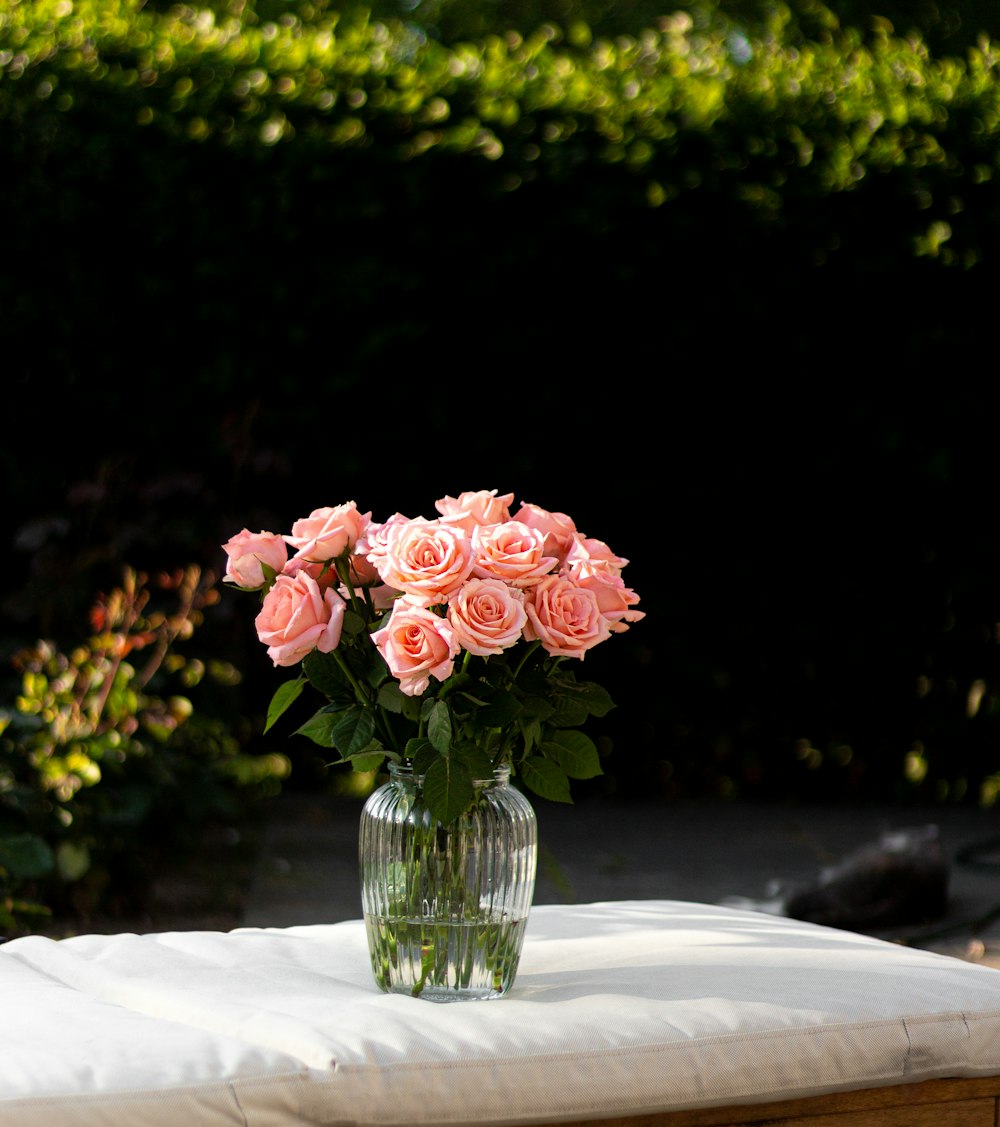 a vase filled with pink roses sitting on top of a table