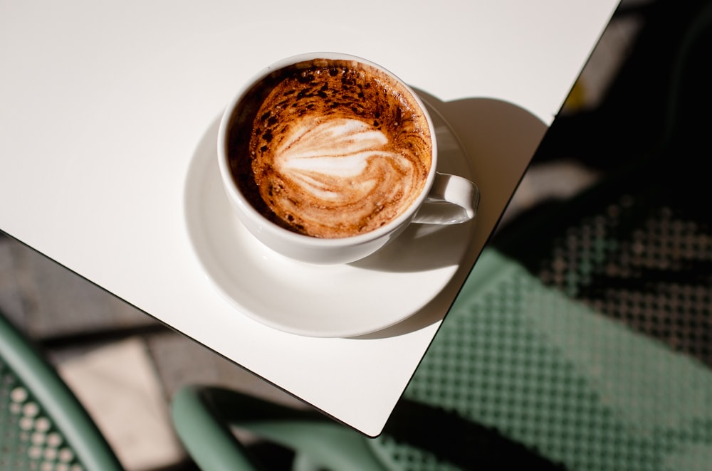 a cup of coffee sitting on top of a white table