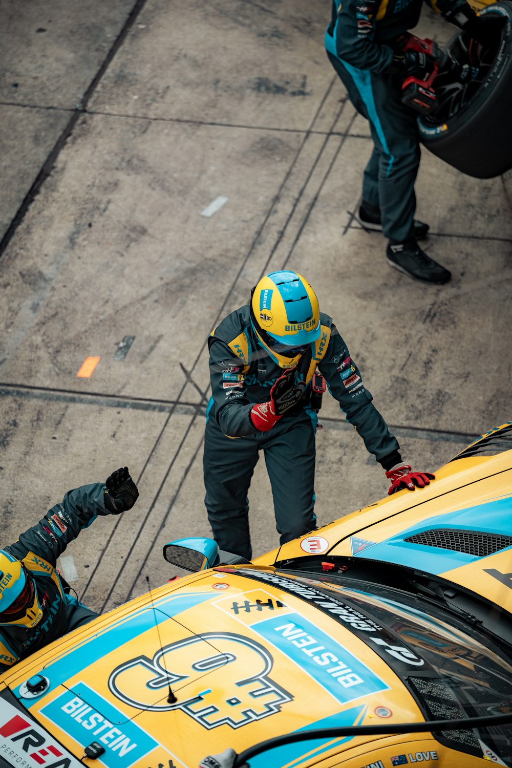 a man standing next to a yellow race car