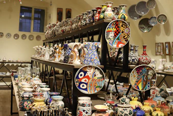 Colorida variedad de cerámica de Talavera pintada a mano exhibida en estantes de madera.