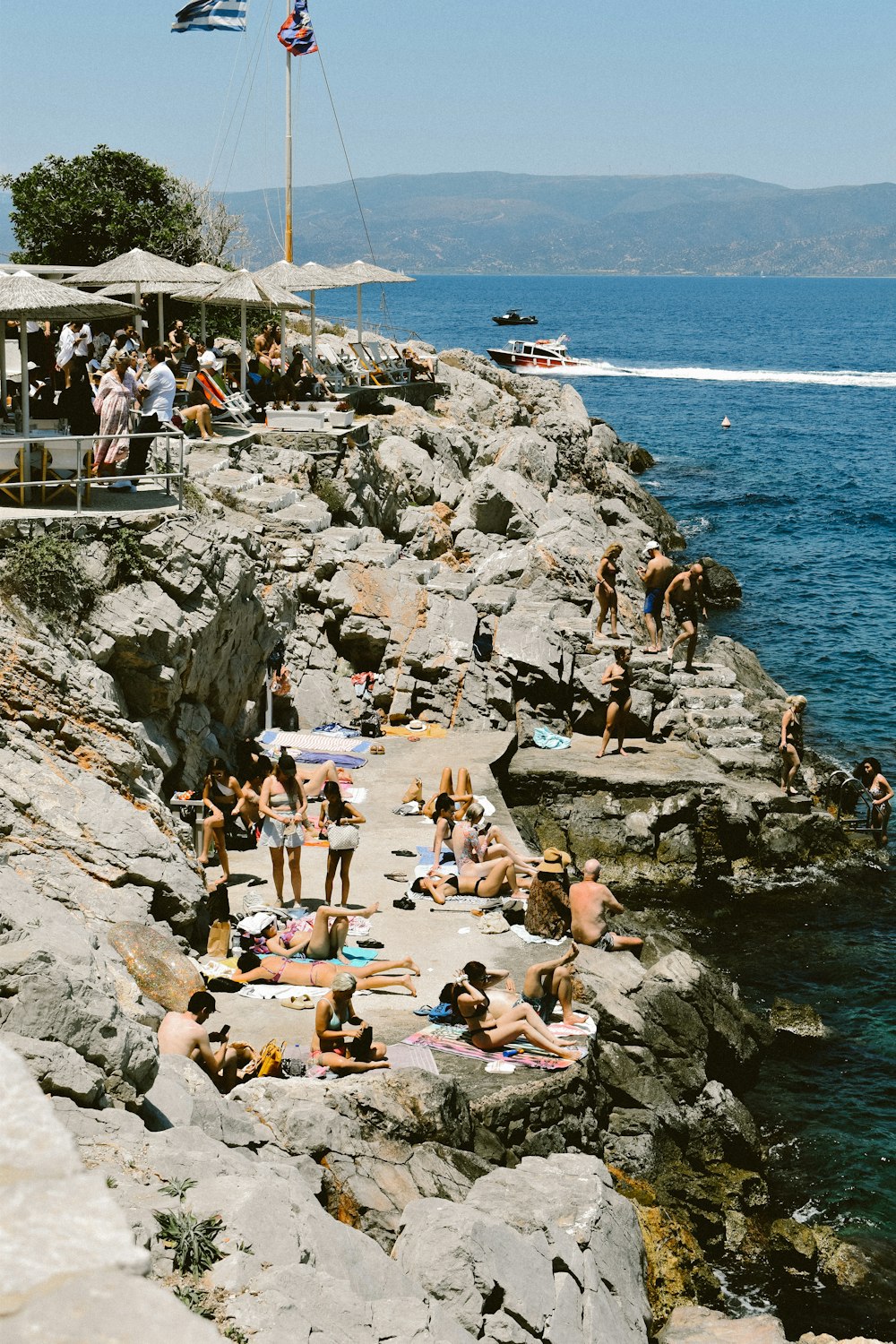 a group of people sitting on top of a rocky cliff next to the ocean