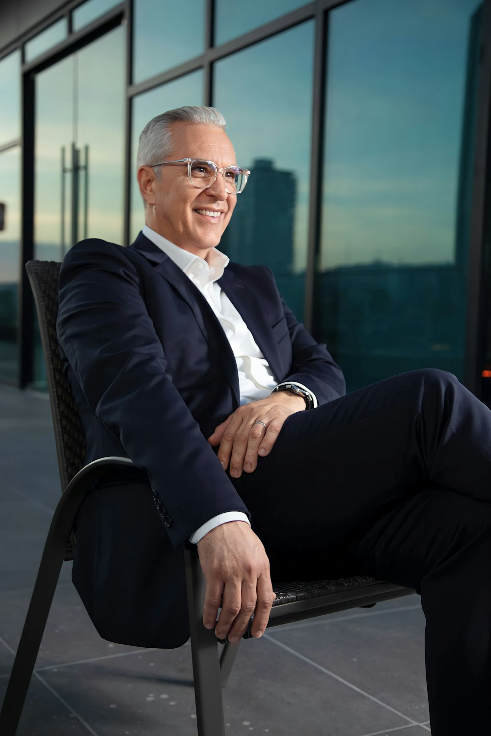 a man in a suit and glasses sitting on a chair