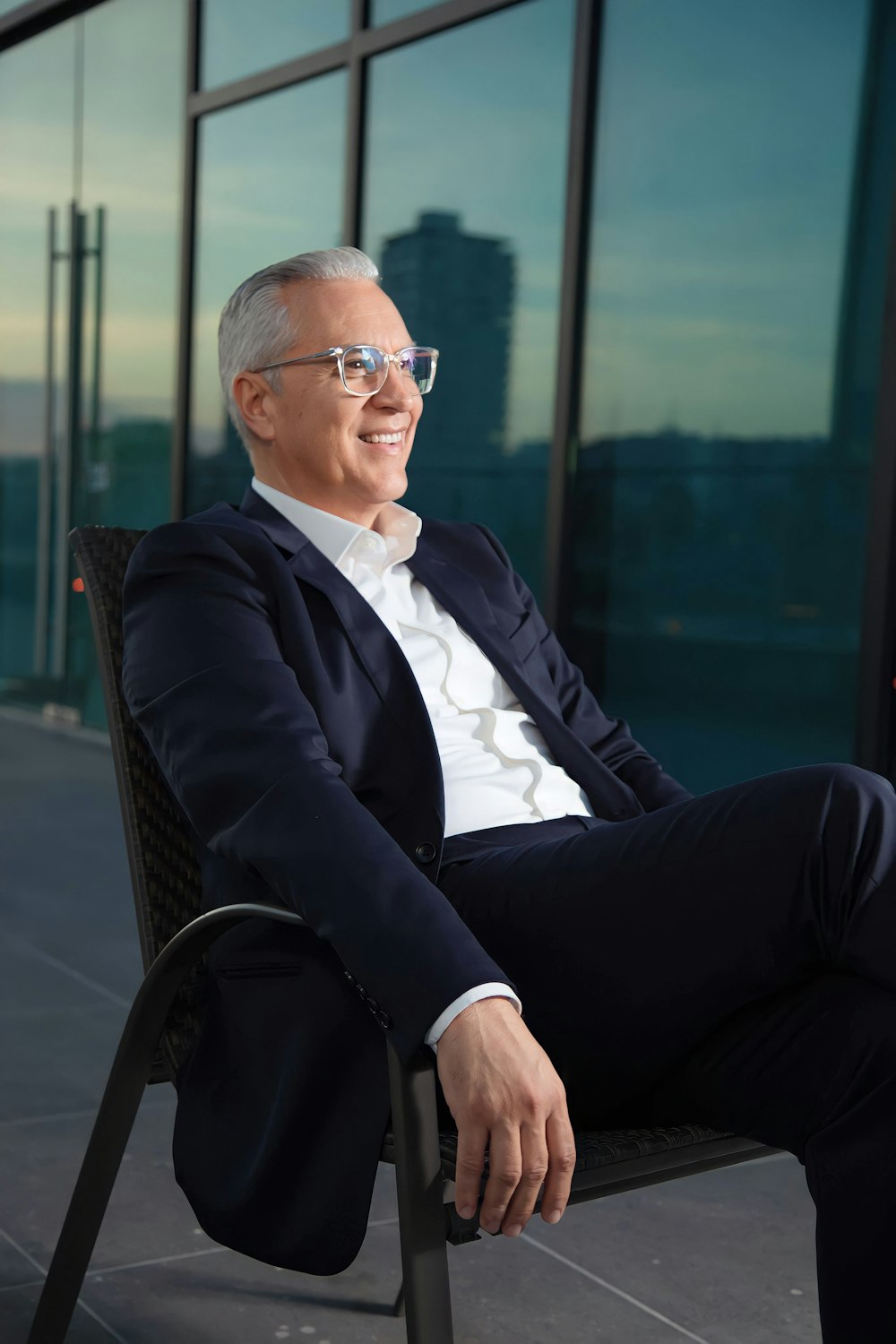 a man in a suit and glasses sitting on a chair