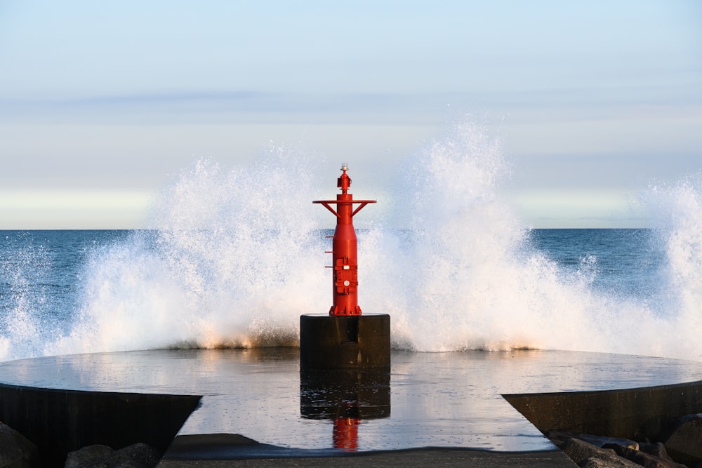 a red fire hydrant in the middle of a body of water