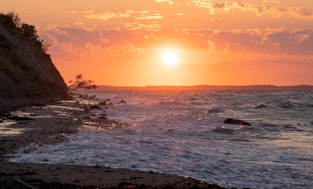 the sun is setting over the ocean with waves