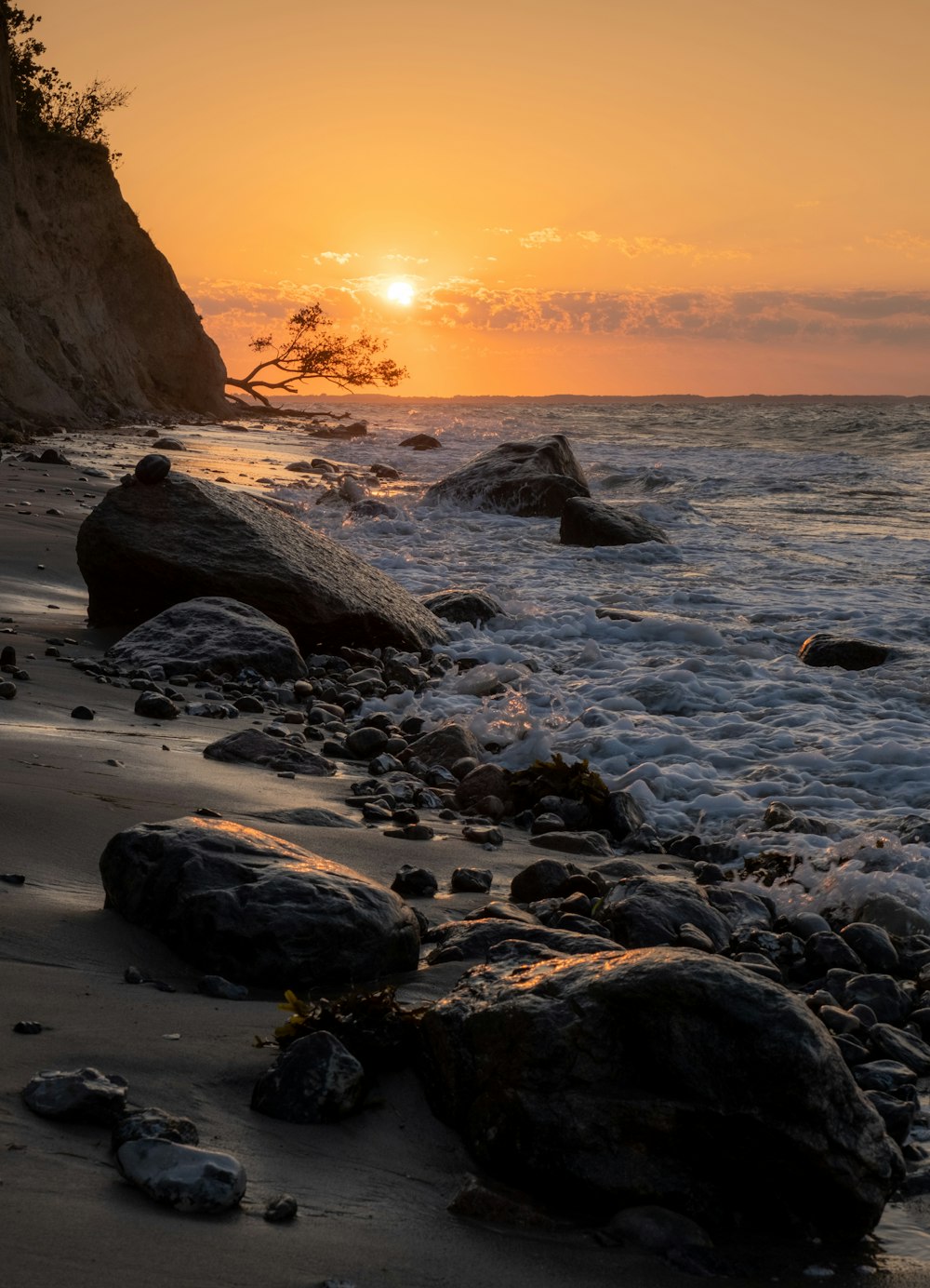 the sun is setting over the water at the beach