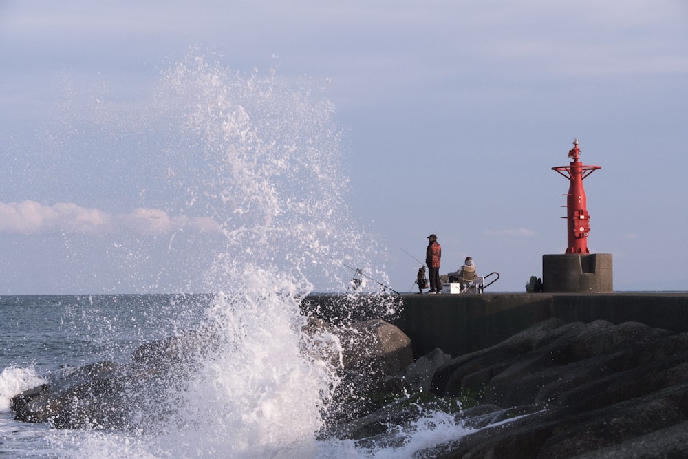 a group of people standing on top of a rock next to the ocean