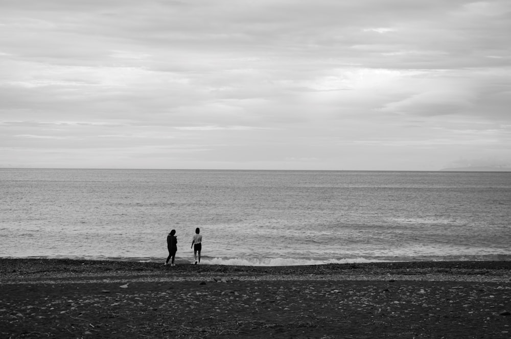 a couple of people standing on top of a beach