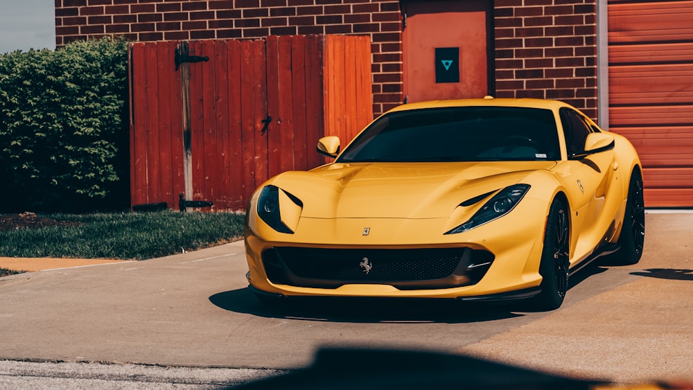 a yellow sports car parked in front of a brick building