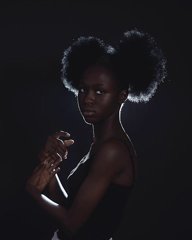 Portrait of a black woman with an afro hairstyle, softly illuminated by a white background.