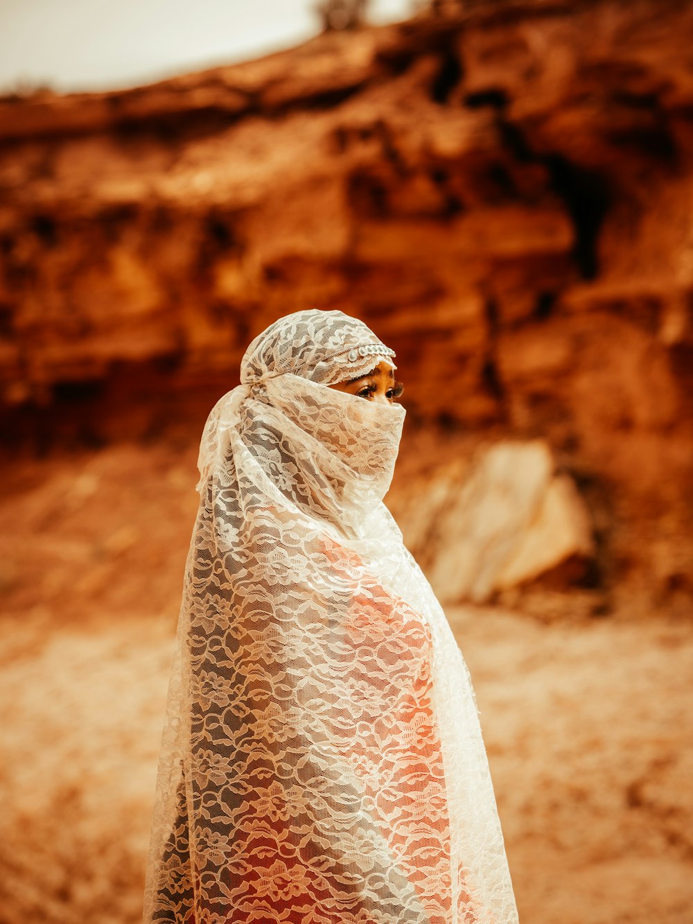 a woman in a white shawl standing in a desert