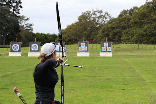 Veteran practicing archery on a sunny day with targets set up in the open field.
