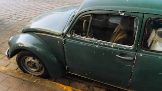 an old green car parked on the side of the road