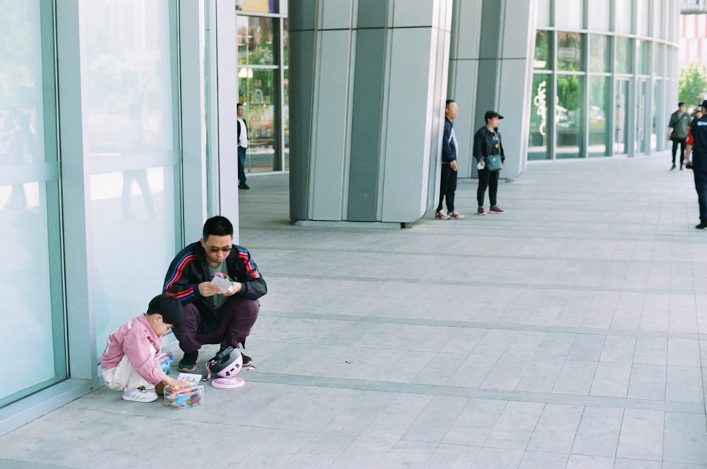 a man sitting on the ground next to a little girl