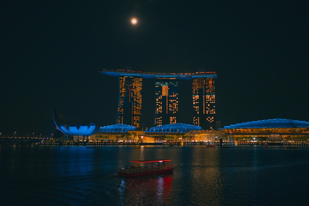 a boat in the water in front of a city at night