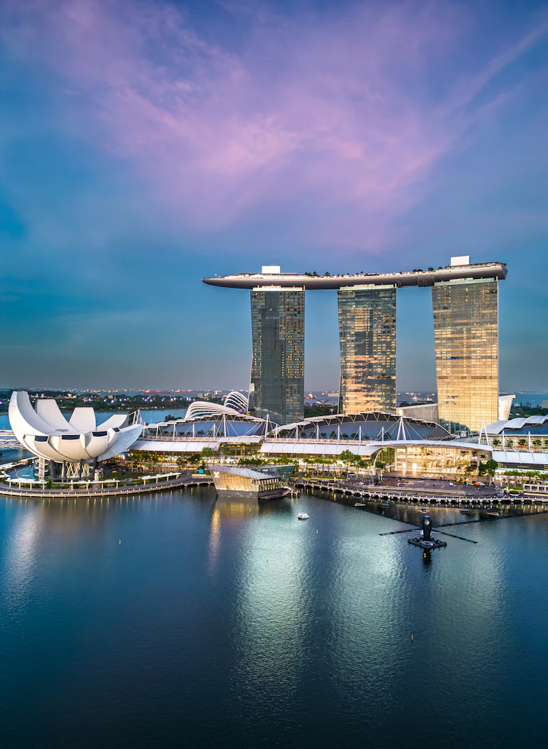 Singapore's Marina Bay waterfront at dusk, towers reflected in the water