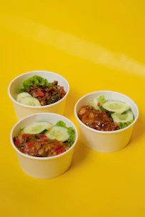 Black bowls with transparent lids filled with colorful food.