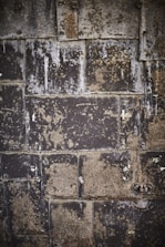 A series of old, weathered metal plates with rivets and rust patches. The surface is uneven, with various shades of dark gray and brown, revealing an industrial, worn look.
