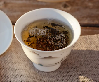 Close-up of tea leaves swirling in a delicate porcelain cup under soft light.